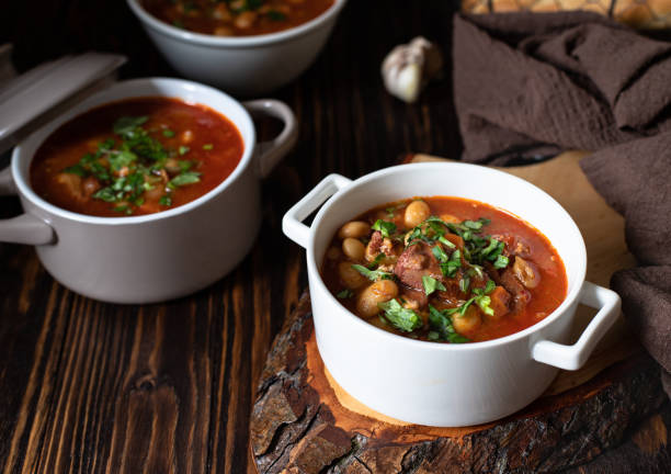 istock Bean soup with meat and vegetables served on a rustic board and wooden table with bread and garlic. Traditional Balkan soup Pasulj (Grah). Close-up, selective focus 1219787297