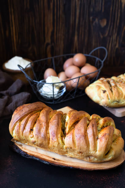 A traditional salty pie of Russian cuisine called kulebyaka. Ingredients for the dough butter, flour, eggs. Two closed pies with different fillings, the first with meat and mushrooms, the second with cabbage. Dark rustic background. Close-up un pastel salado tradicional de la cocina rusa llamado kulebyaka. ingredientes para la masa de mantequilla, harina, huevos. dos pasteles cerrados con diferentes rellenos, el primero con carne y setas, el segundo con repollo. fondo rústico oscuro. primer p