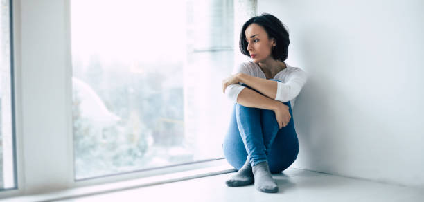 la femme dans la dépression regarde par la fenêtre - women depression window sadness photos et images de collection