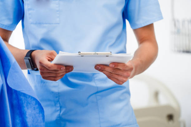 istock Male doctor on duty in scrubs reading patient's information from checklist document, selective focus on folder, health and medical concept. 1219794770