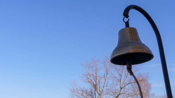 zbliżenie starego dzwonka ogniowego z brązu skool na klasycznym tle błękitnego nieba. koncepcja alarmu pożarowego. - service bell flash zdjęcia i obrazy z banku zdjęć