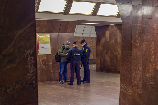 Moscow, Russia - April 17, 2020: Policeman checks the documents of citizen a platform in subway. Connection with COVID-19, access control effect.