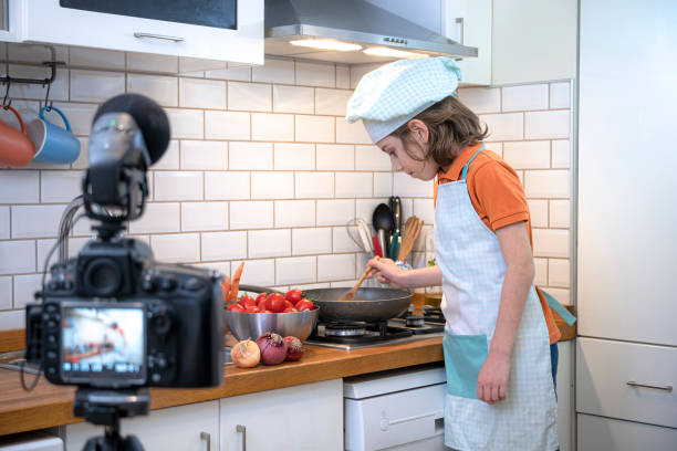istock Child making recording on a tripod mounted camera in kitchen. 1219802017