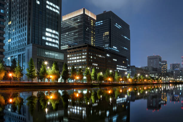 Twilight view of skyline at Tokyo Station with water reflections at Chiyoda, Japan Illuminated buildings and skyscrapers with reflections in water at Tokyo Station in Chiyoda, Tokyo, Japan low angle street japan stock pictures, royalty-free photos & images