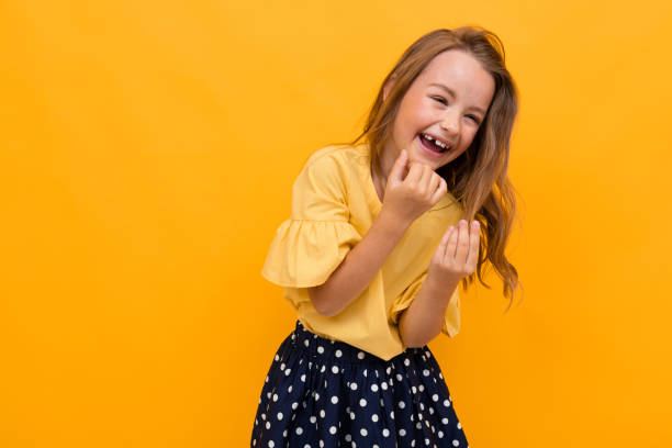 istock charming girl child laughs on an orange background 1219814420