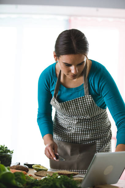 istock Young woman checking following steps for a recipe 1219814630