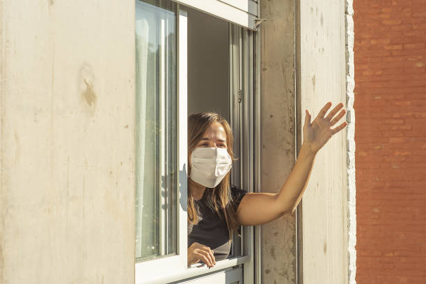istock Woman in the windows during quarantine greeting a neighbor 1219819921