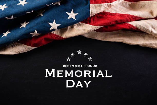 istock Happy Memorial Day. American flags with the text REMEMBER & HONOR against a blackboard background. May 25. 1219823782