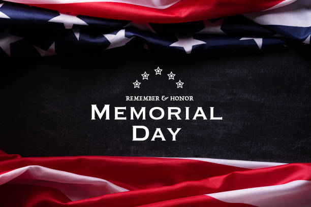 istock Happy Memorial Day. American flags with the text REMEMBER & HONOR against a blackboard background. May 25. 1219824588