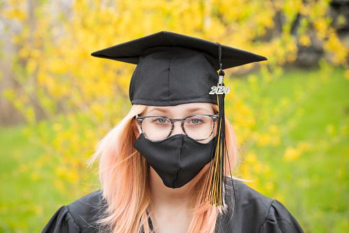 A graduate of the class of 2020 during the coronavirus pandemic with a matching face mask on.