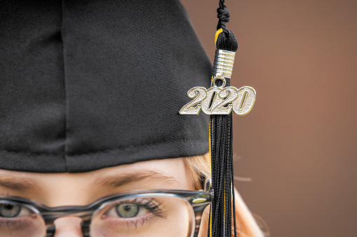 A close up of 2020 on a tassel hanging from the cap of a teenage girl.