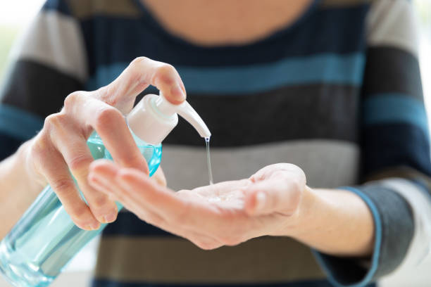 istock Woman cleaning and disinfecting hands with hand sanitizer close up 1219829789