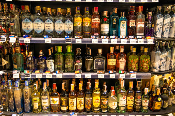 assortimento di liquori tra cui gin, vodka, rum, whisky, ecc. sugli scaffali con cartellino del prezzo in un supermercato. - liquor store foto e immagini stock