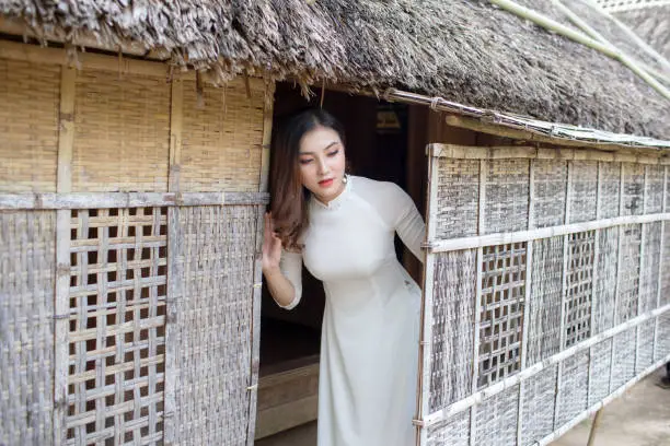 Vietnamese girl wearing a white Ao Dai and holding a conical hat at Hoang Tru, Kim Lien, Nam Dan. The Ao dai ( long-dress Vietnamese) is traditional costume of Vietnamese woman