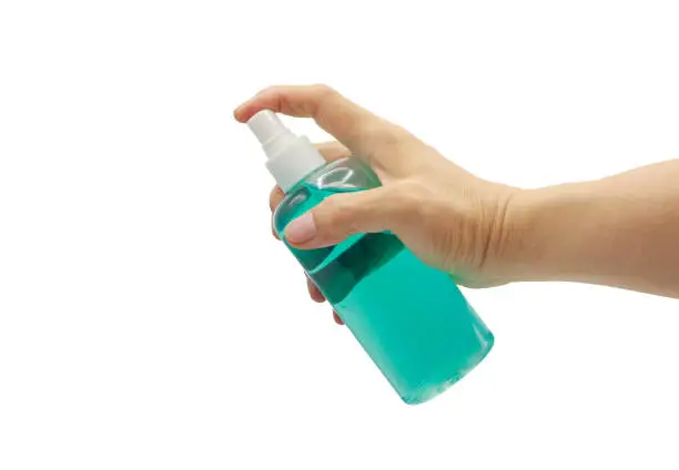 Photo of Closeup hand holding and press on blue alcohol spray bottle isolated on white background