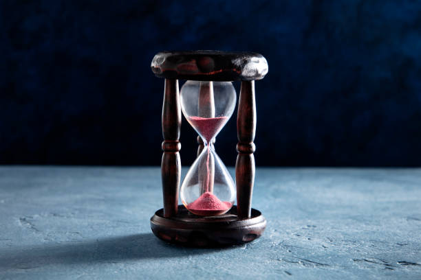 istock Time concept. An hourglass with sand falling through, on a dark background 1219833010