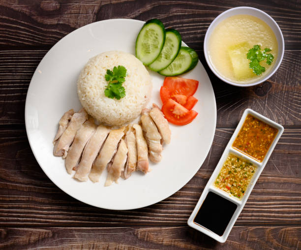 istock Hainanese chicken rice with soup and three sauces on dark wood table texture 1219833143