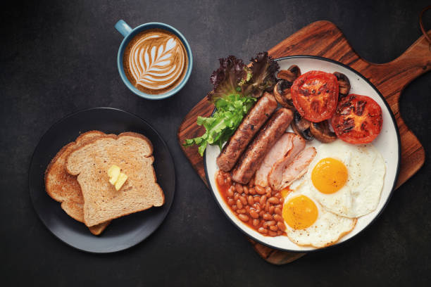 Full English Breakfast with Latte Art on dark table sausage eggs bean bacon tomatos mushroom Full English Breakfast with Latte Art on dark table sausage eggs bean bacon tomato mushroom english breakfast stock pictures, royalty-free photos & images
