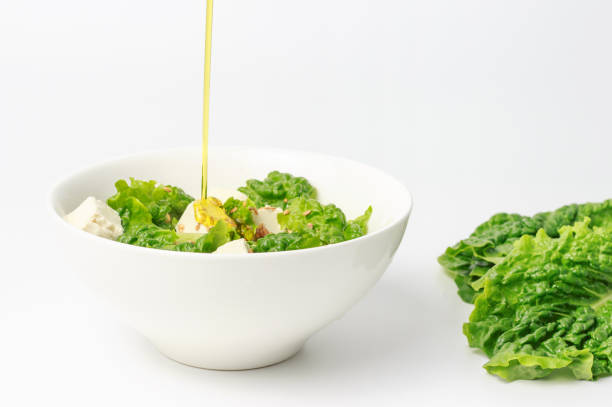 dans un bol avec salade verte et le tofu est versé avec de l’huile d’olive, gros plan, vue supérieure - salad green pouring dip photos et images de collection