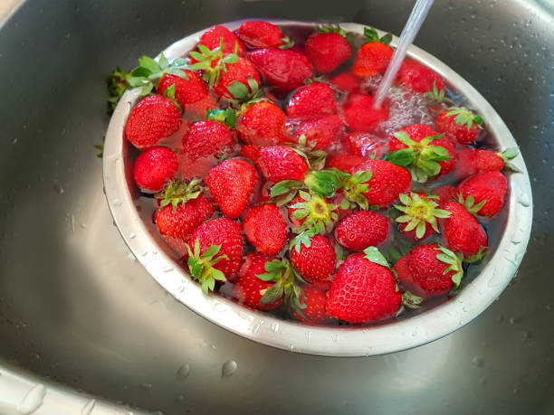 新鮮な赤熟したヘルシーボウルでイチゴを洗う - washing fruit preparing food strawberry ストックフォトと画像