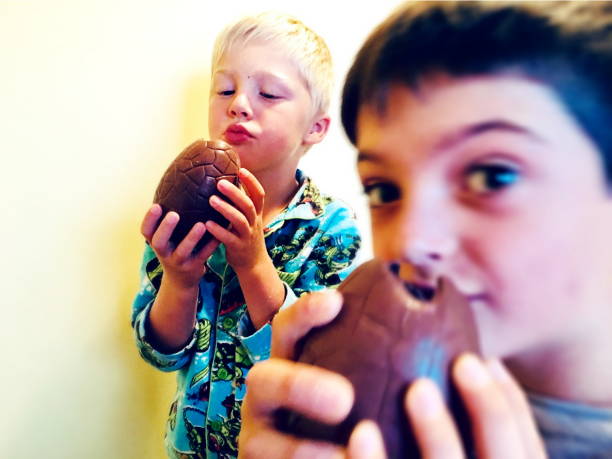 bambini che mangiano uova di pasqua - easter easter egg child chocolate foto e immagini stock