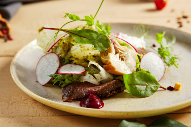 istock Roast beef, artichokes and poached egg salad in white plate closeup view 1219848140