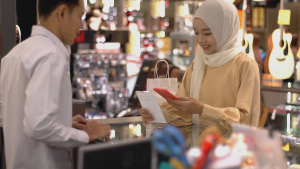 femme musulmane asiatique utilisant le paiement sans contact - bar code biometrics people one person photos et images de collection