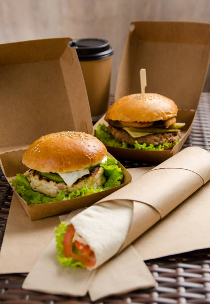 istock two different burgers in boxes and chicken roll with vegetables on a paper sheet. vertical view 1219850735