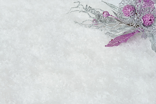 Christmas decoration with pink-silver flowers and branches on a white snow background, with space for text