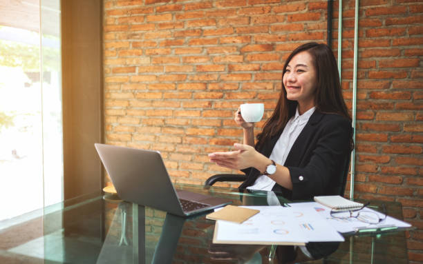 istock businesswoman talking and drinking coffee while using laptop computer for working in office 1219855312