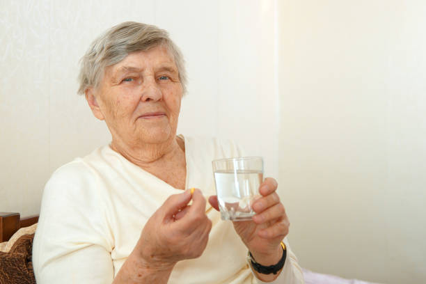 an elderly woman is going to swallow a medicine - surgical glove human hand holding capsule imagens e fotografias de stock