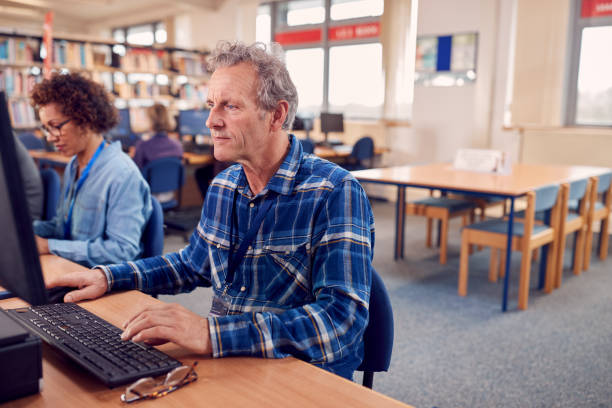 istock Group Of Mature Adult Students In Class Working At Computers In College Library 1219860631