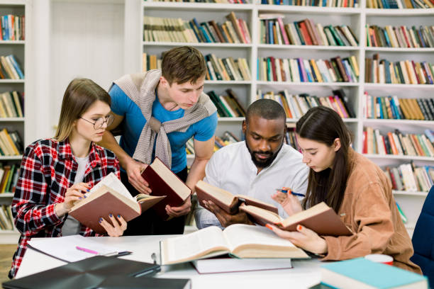 istock Smart confident young multiethnical students reading books at the table, looking for information and study together at college library 1219860820