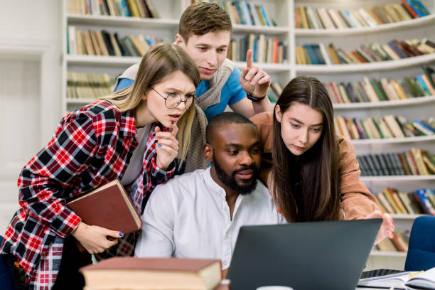 istock Young mixed race students or coworkers, concentrated on the study, project, working together in the reading room of university library using laptop computer and different books 1219861002