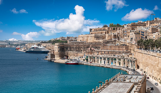 Beautiful landscape with historical walls and buildings at the harbour of Valletta, capital of Malta. Blue sky and white clouds on a summer vacation day.