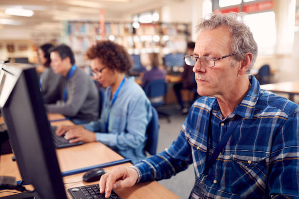 istock Group Of Mature Adult Students In Class Working At Computers In College Library 1219861043