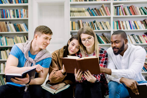 istock Group of young friends multiracial students, sitting in campus library, reading books while preparing for exams, test or homework. Happy book day, education and library concept 1219861146