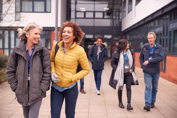 Group Of Smiling Mature Students Walking Outside College Building Group Of Smiling Mature Students Walking Outside College Building nontraditional student photos stock pictures, royalty-free photos & images