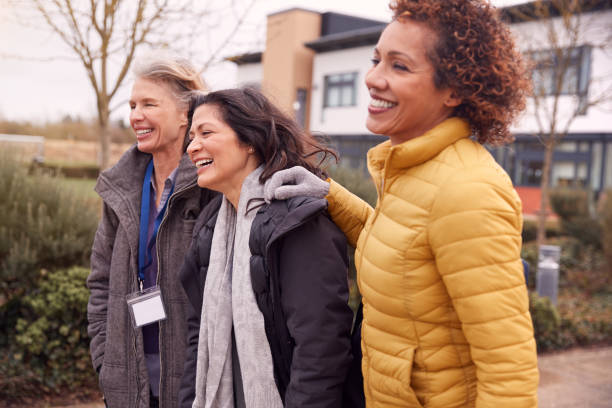 group of smiling female mature students walking outside college building - night school imagens e fotografias de stock