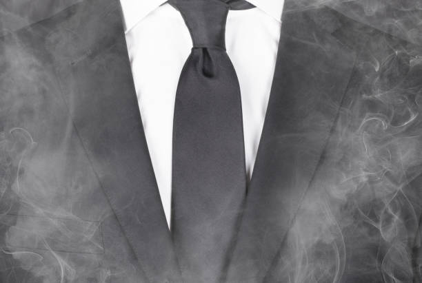 homme dans un costume noir et cravate noire, restant dans la fumée, plan rapproché - suit necktie close up gray photos et images de collection