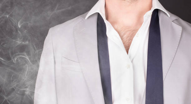 homme dans un costume gris avec la cravate bleue, restant dans la fumée, plan rapproché - suit necktie close up gray photos et images de collection