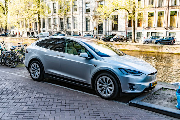 Tesla parked in Amsterdam during a bright spring day A bright spring day in Amsterdam, Netherlands with a Tesla Model X parked on an Amsterdam street beside a canal. tesla model x stock pictures, royalty-free photos & images