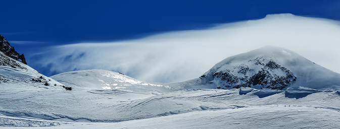 White winter mountains covered with snow in blue cloudy sky. Alps. Austria. Pitztaler Gletscher. Wildspitzbahn. Winter season