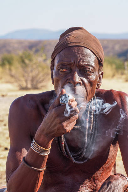 opuwo, namibia: vecchio uomo namibiano che fuma un sigaro, visto a opuwo, capitale della regione di kunene in namibia - student outdoors clothing southern africa foto e immagini stock