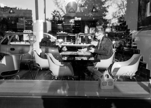 Belgrade, Serbia, Nov 26, 2019: A reflective insight into a snack bar with a couple having a meal (B/W).