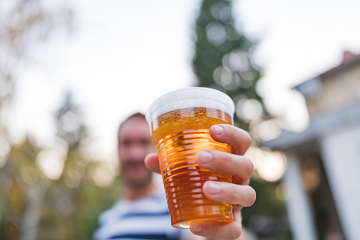 Man holding cold glass of beer outdoors.