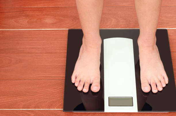 istock Close up children's foot standing on weight scale with copy space. 1219871301