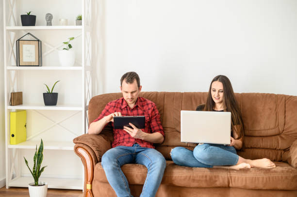 istock Young married couple on a sofa with gadgets 1219871363