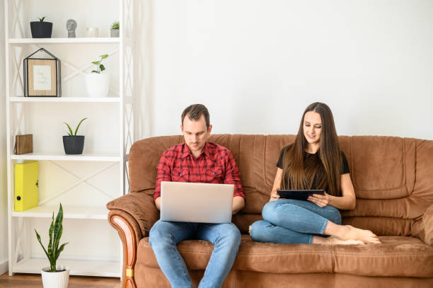 istock Young married couple on a sofa with gadgets 1219871371