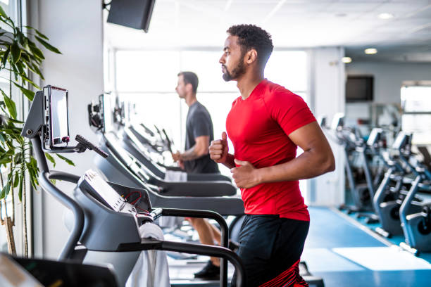 Fit and Focused Mid Adult Men Using Treadmills at Gym